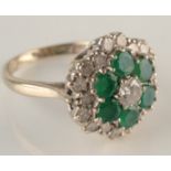 An 18ct. white gold ring set a lobed emerald and diamond cluster.