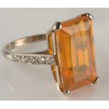 A white gold ring set a large emerald cut fire opal with diamond set shoulders.