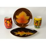 A Poole shape 83 vase, another shape 83 with stepped side, a Poole Aegean leaf tray, diameter 25.