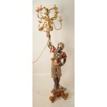 A carved and polychrome painted blackamoor figure, holding a gilt metal ten branch candelabrum,