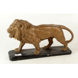 A gilt painted composition model of a lion, on a black painted base, height 24cm, length 38.