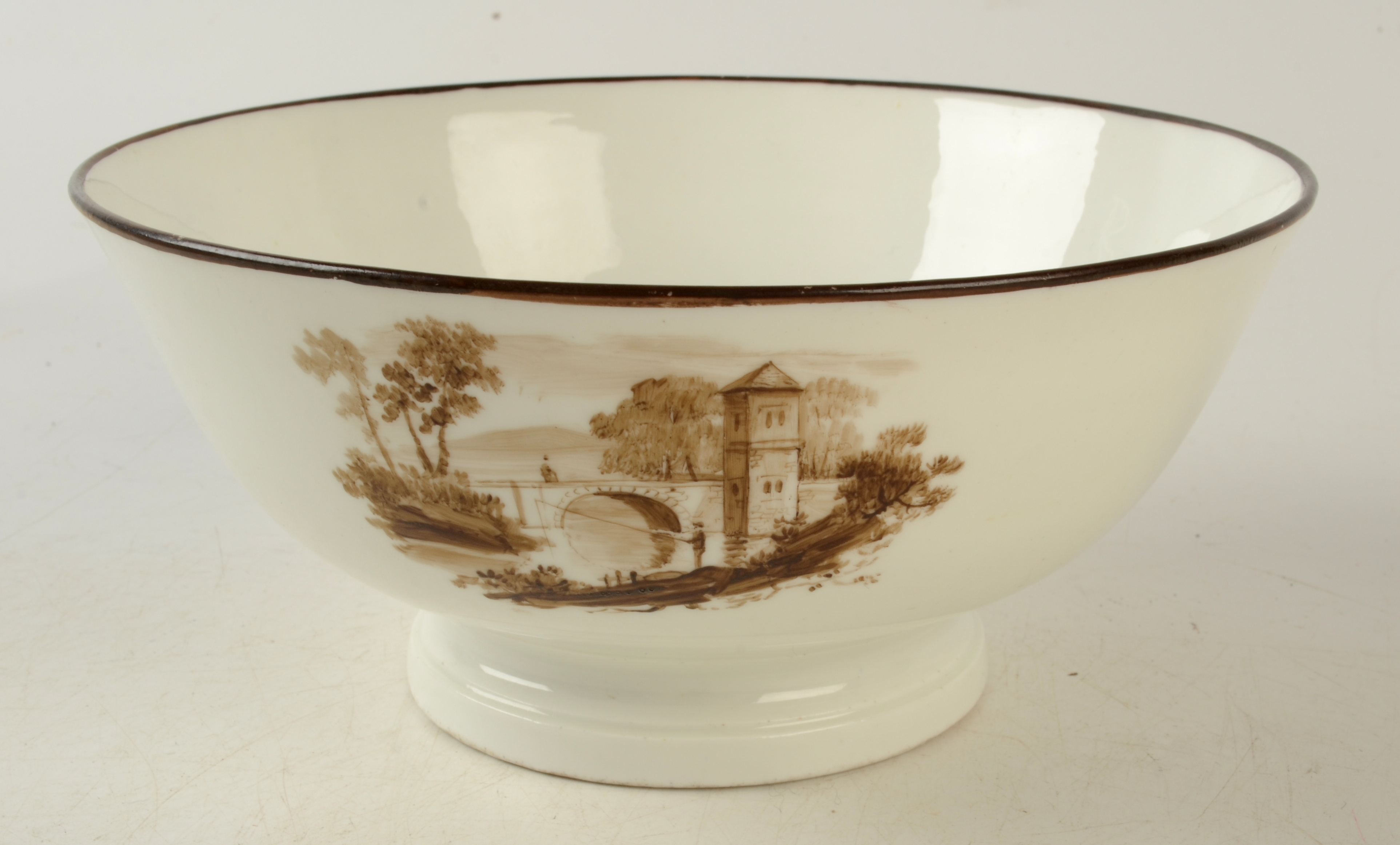 An 18th century Swansea porcelain bowl painted with three sepia landscape vignettes,