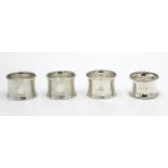 A pair of engine turned silver napkin rings, together with two other silver napkin rings, 2.2oz.