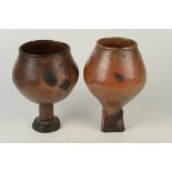 Two African glazed pottery vessels of bulbous form on stemmed bases with primitive incised