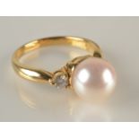 An 18ct. gold ring set an 8.4mm pearl flanked by diamonds.