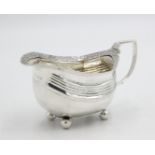 A Georgian silver sauce boat on four ball feet with woven rim and reeded handle, by Crispin Fuller,