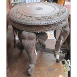 An Indian carved hardwood occasional table, the legs in the form of elephant masks and trunks,