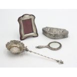 A continental silver straining spoon with a flower shaped bowl on which sits a cherub,