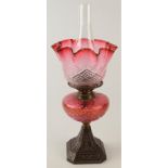 A late Victorian cast iron and cranberry glass oil lamp, height 52.5cm.
