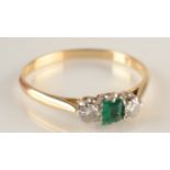 An 18ct gold ring set an emerald between two diamonds.