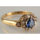 An 18ct gold ring set a sapphire and diamond cluster flanked by diamond shoulders.