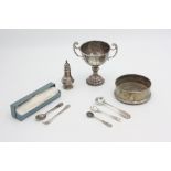 A silver twin handled trophy cup, a silver pepper,