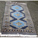 A Pakistan rug, the indigo field with three large polychrome medallions, within multiple borders,