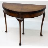 A George III style walnut demi lune tea table, the fold over top on cabriole legs with pad feet,