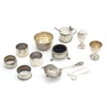 Four silver napkin rings, a tea strainer and stand, a swizzle stick and various condiments,