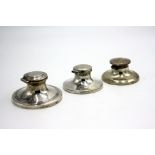 Three silver capstan inkwells.