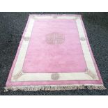 A Chinese carpet, the pink ground with a central ivory medallion, within an ivory field,