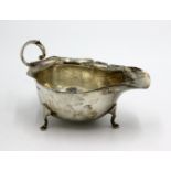 An Asprey & Co silver sauce boat on three cabriole feet and with undulating rim and scroll handle,