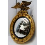 A giltwood convex wall mirror, 20th century, surmounted by a carved eagle, height 57cm, width 42cm.