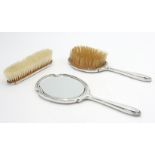 A silver mounted engine turned dressing table mirror and two matching brushes.