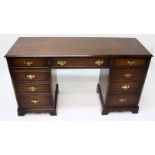 A George III style mahogany pedestal desk, with an arrangement of nine drawers on bracket feet,