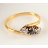 An 22ct yellow gold crossover set with two diamonds and a sapphire.
