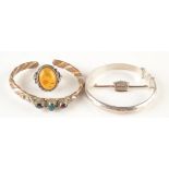 A Cornish Stone Company silver, amber set ring, two bangles and a naval crown brooch.