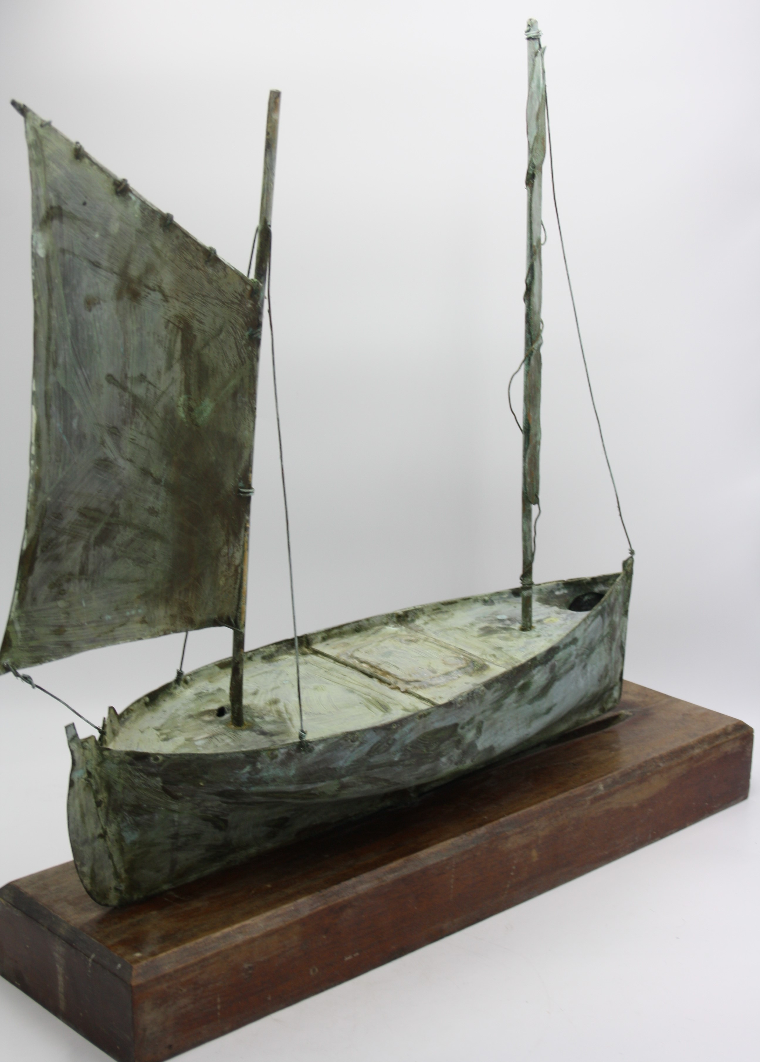 An early 20th century copper weather vane, in the form of a Cornish lugger, mounted on an oak stand,