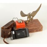 A Zeiss Ikon camera with accessories and film, a card trick and brass model of an eagle.