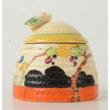A Clarice Cliff honey pot in the form of a skep, the lid with bee finial, height 7.5cm.
