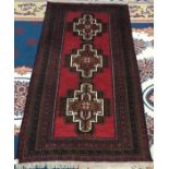 A Belouch rug, the madder field with three stepped brown medallions, within multiple borders,