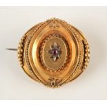 A Victorian matte gold brooch with central ruby.