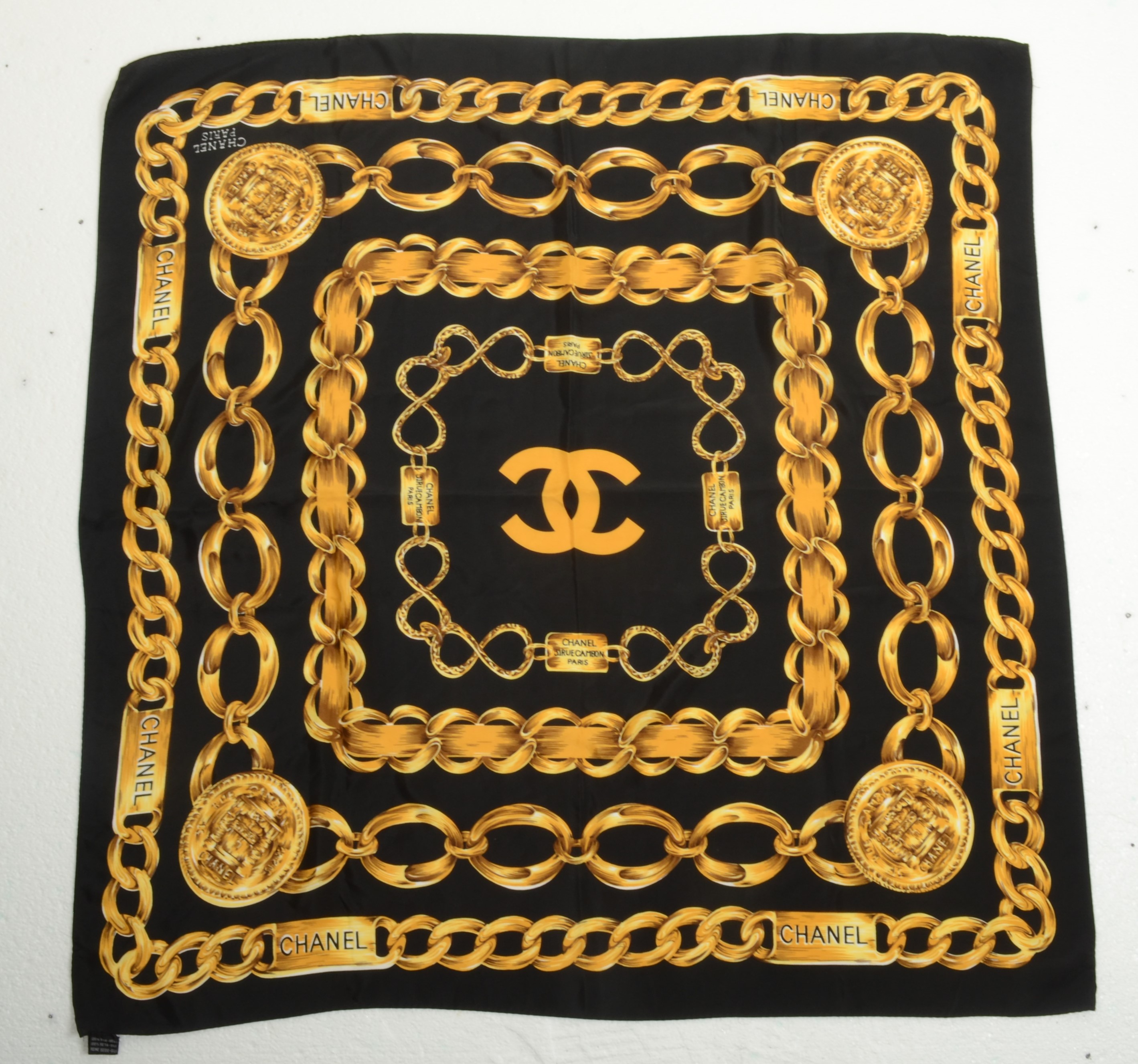 A Chanel silk scarf, black with gold chain link design, 85cm x 85cm.