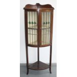 An Edwardian inlaid mahogany bow front standing corner cupboard, with a pair of lead lined,