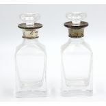 A pair of plain glass small decanters, each with plain silver collar, height 14.5cm.