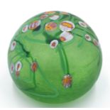 A Norman Stuart Clarke studio glass paperweight, with stylised flower decoration on a green ground,