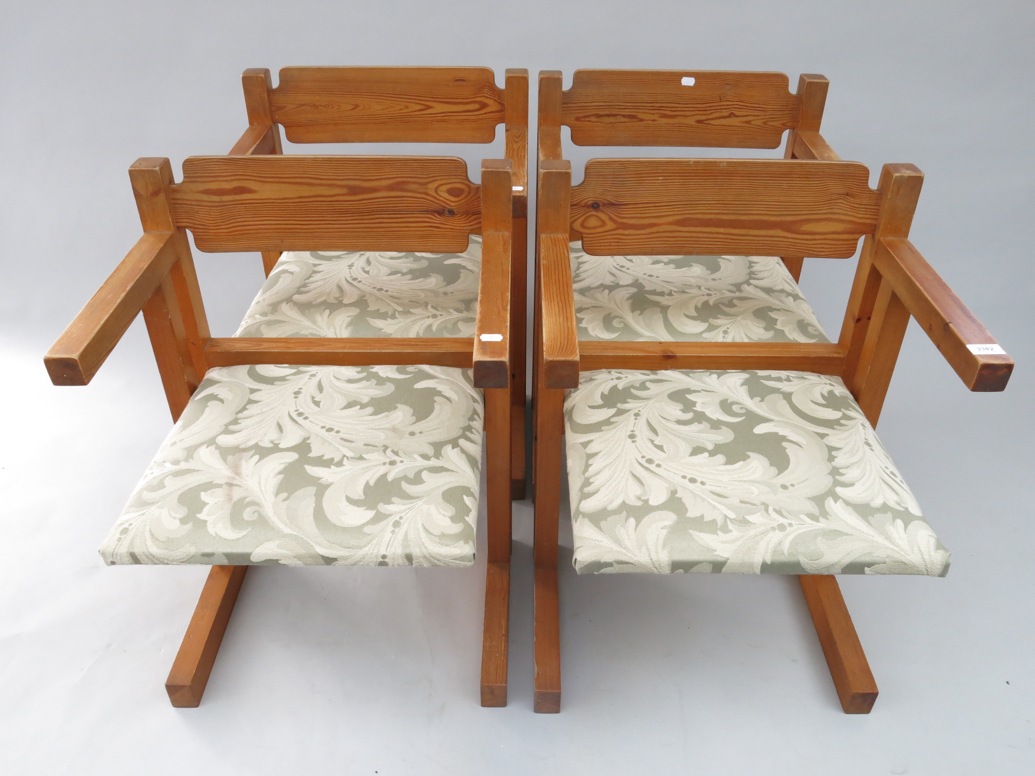 A set of four pine armchairs, each with a padded seat.
