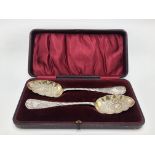 A pair of silver berry spoons, the scalloped bowls with embossed floral decoration, 3.8oz, cased.