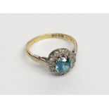 An 18ct gold ring set of diamond and pale blue stone cluster.