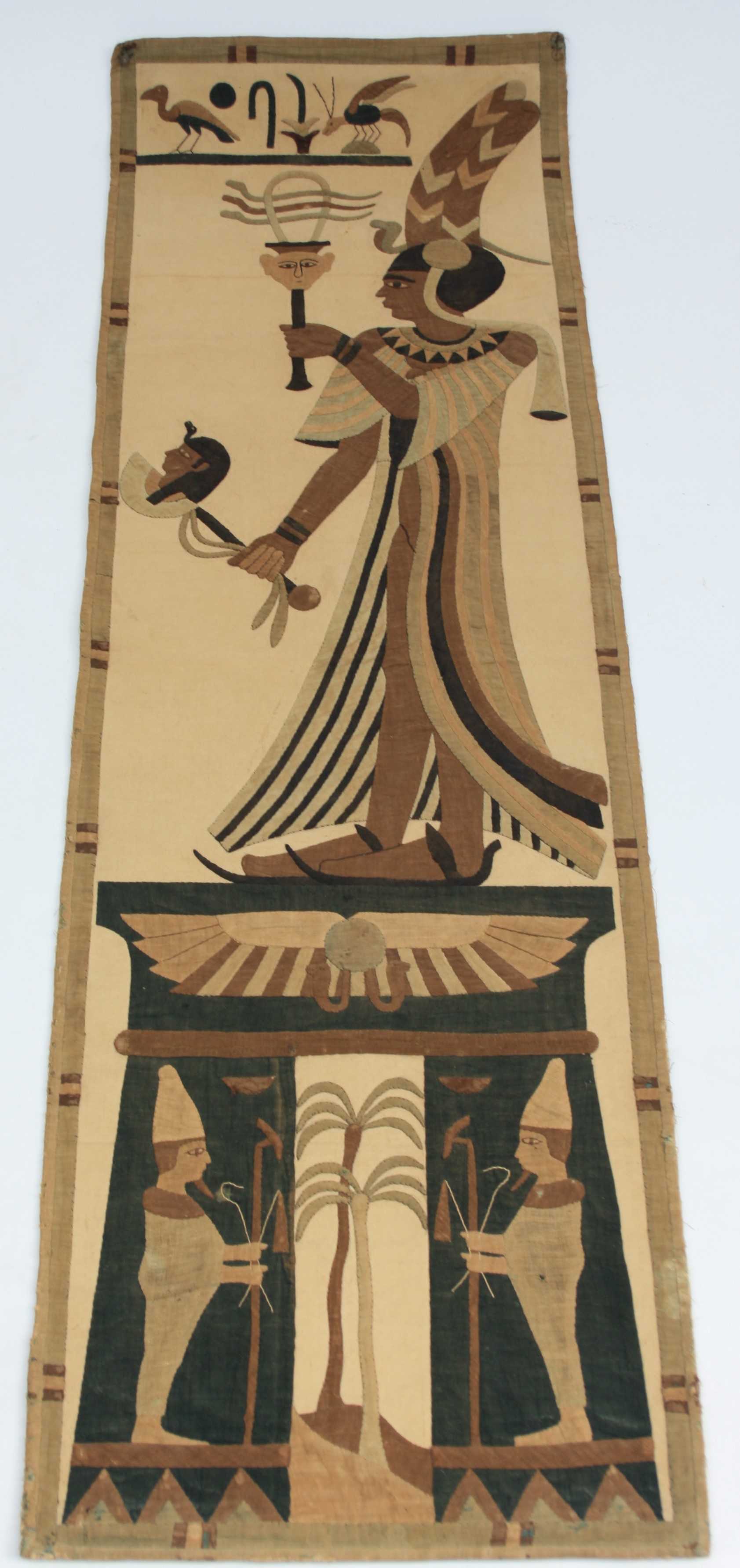 A linen wall hanging, early 20th century, worked in colours with an Egyptian figure and motifs,