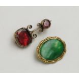 A gold brooch set with red stones and gold mounted cufflink element set with jade.