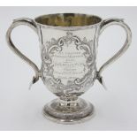 A footed silver trophy cup with acanthus and floral repousse decoration.