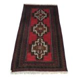 A Belouch rug, the madder field with three stepped brown medallions, within multiple borders,