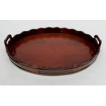 A George III style mahogany oval tray, with shaped brass bound gallery and twin handles,