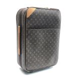 A Louis Vuitton roll along monogram suitcase, cow hide leather trim, fabric lined interior,