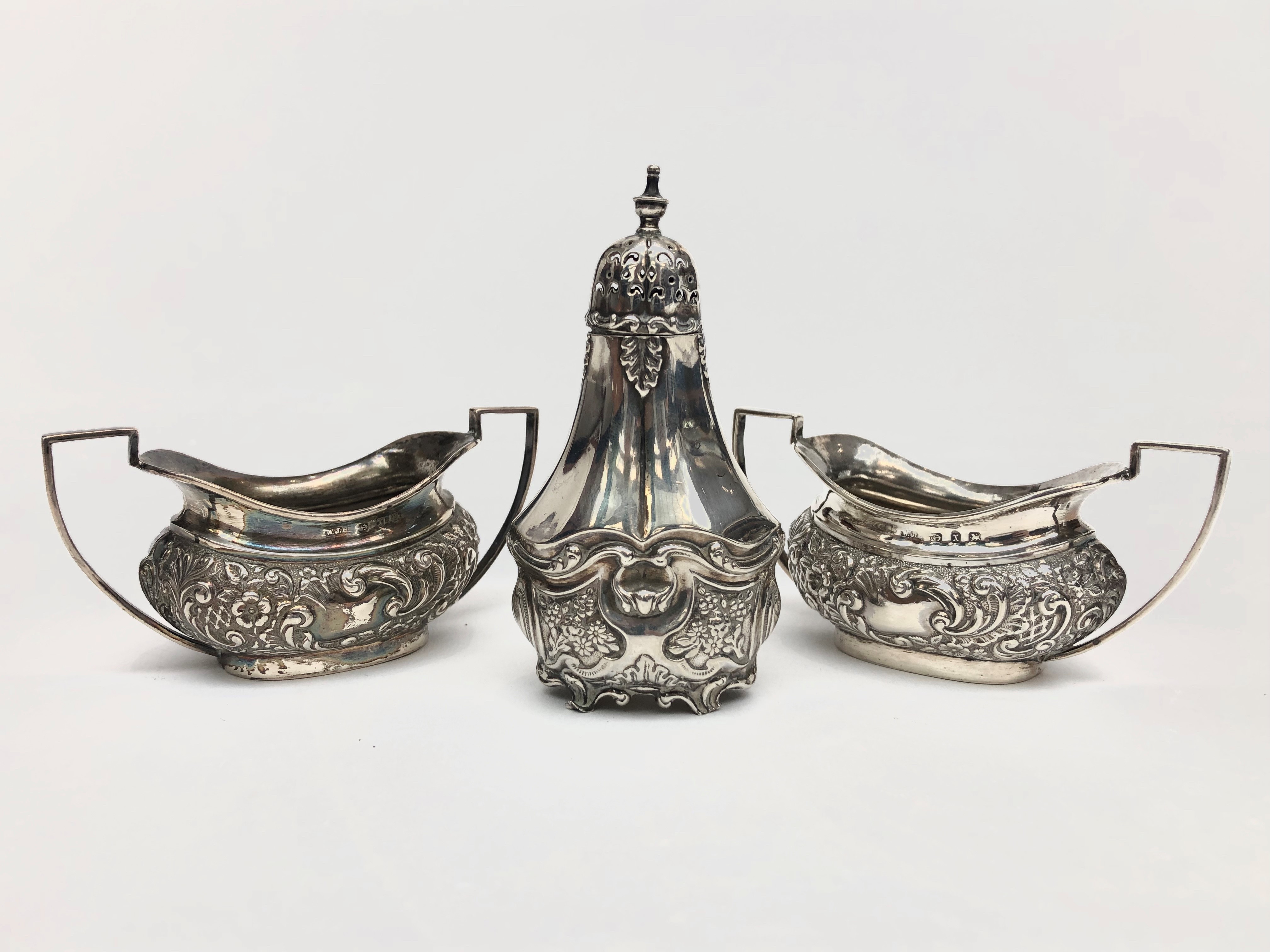 A pair of silver open salts with repousse decoration, together with a silver pepper, 3.7oz.