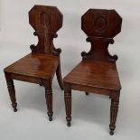 A pair of Regency mahogany hall chairs, each with a shaped solid back and seat,