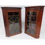 A near pair of Sheraton period mahogany hanging corner cupboards with elliptical box wood strung