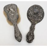 A silver mounted hand mirror with floral repousse decoration,