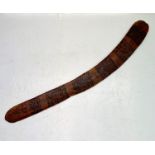 A wooden boomerang, decorated with horizontal bands, length 69cm.